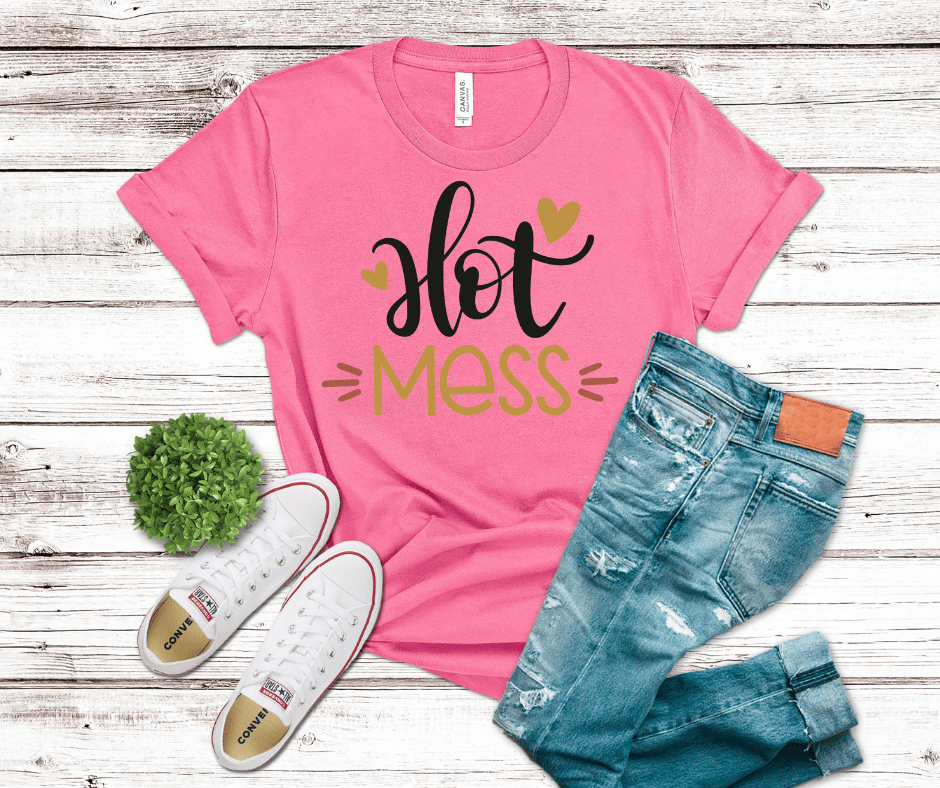 DTF transfer featuring the words “Hot Mess” in black script with gold accents and heart details, minimalist cute style on a pink background.