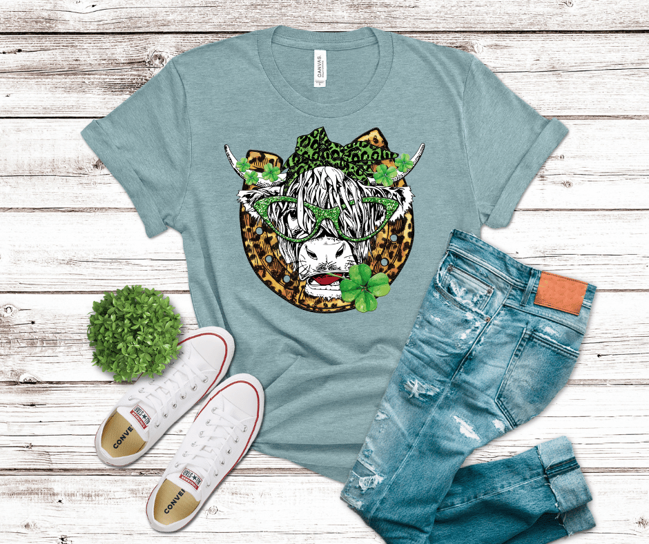 Western cow skull DTF transfer featuring a horseshoe, green shamrocks, leopard-print accents, and glittery green sunglasses with a bow.