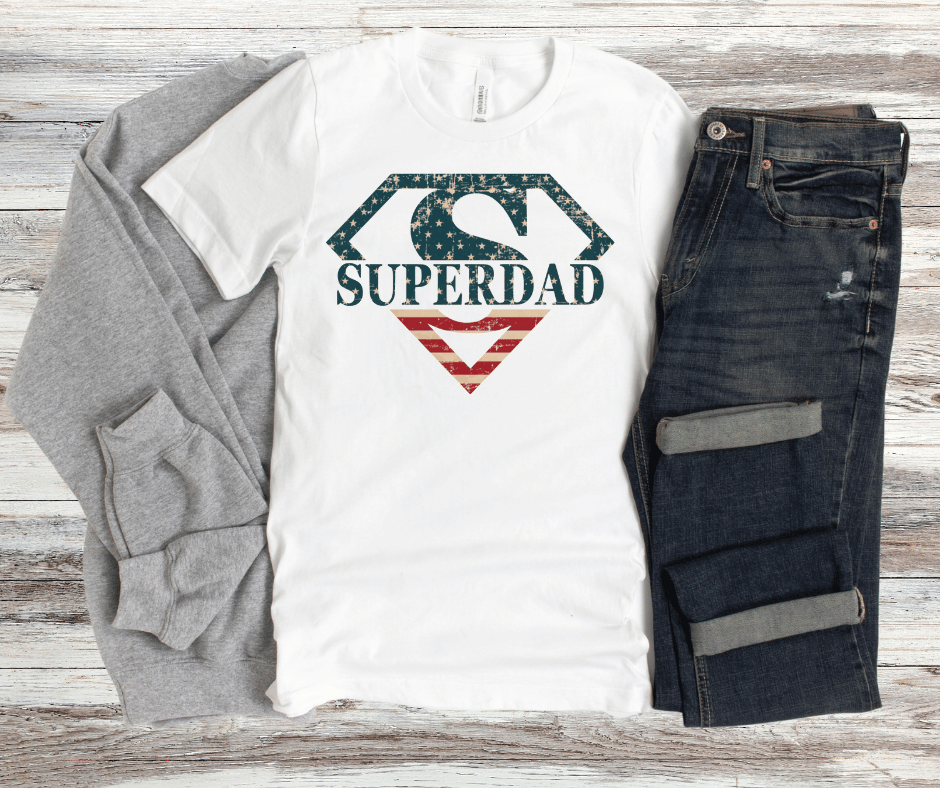 Patriotic Superdad shield graphic with distressed American flag colors in a superhero emblem style, high-quality DTF transfer design for dad apparel.