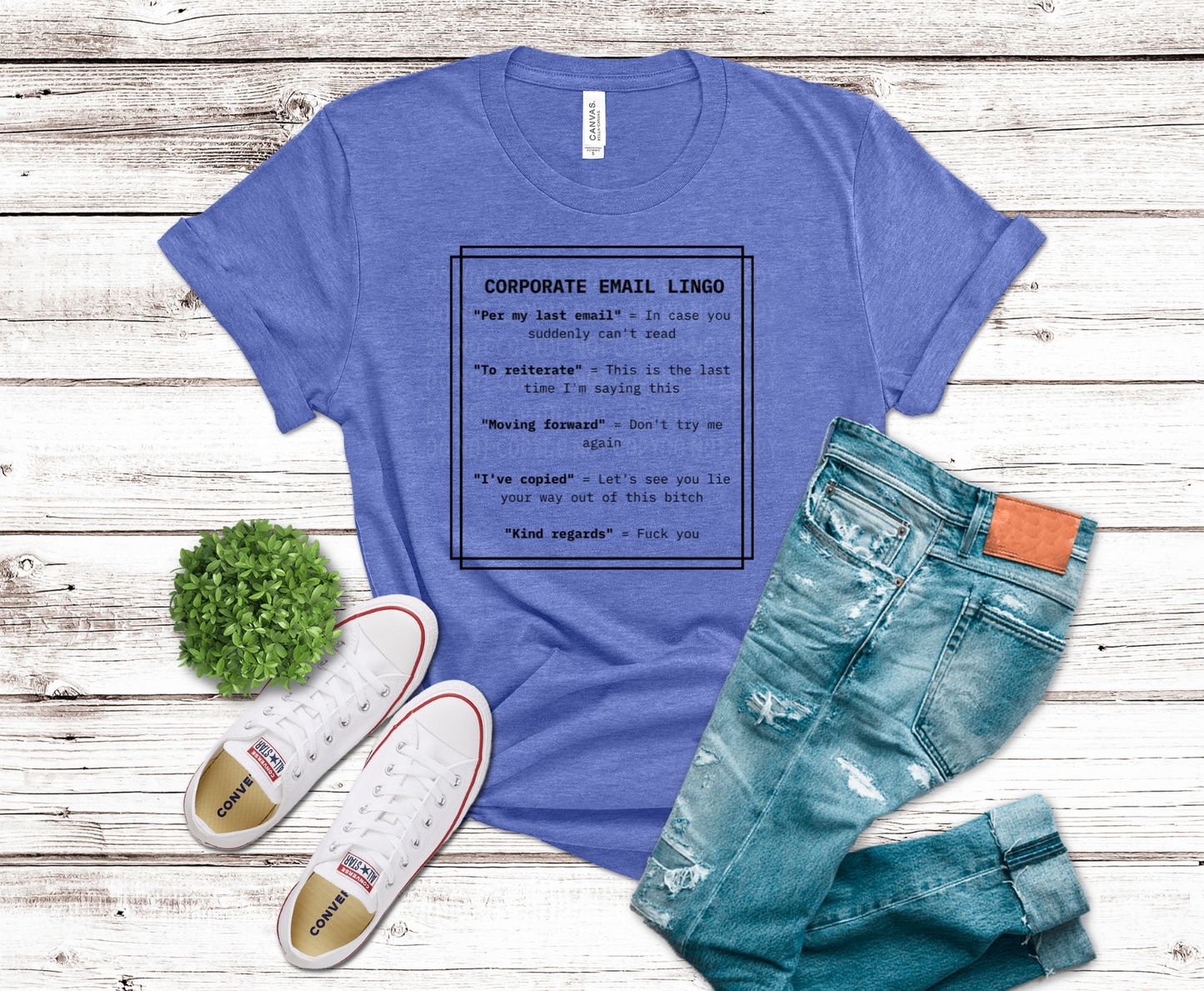 Blue t-shirt with text, jeans, and sneakers on a wooden surface