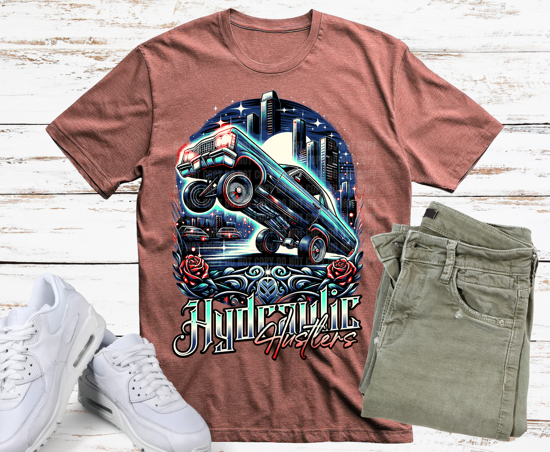 Brown t-shirt with a graphic design of a truck and roses, paired with white sneakers and green jeans on a wooden surface.