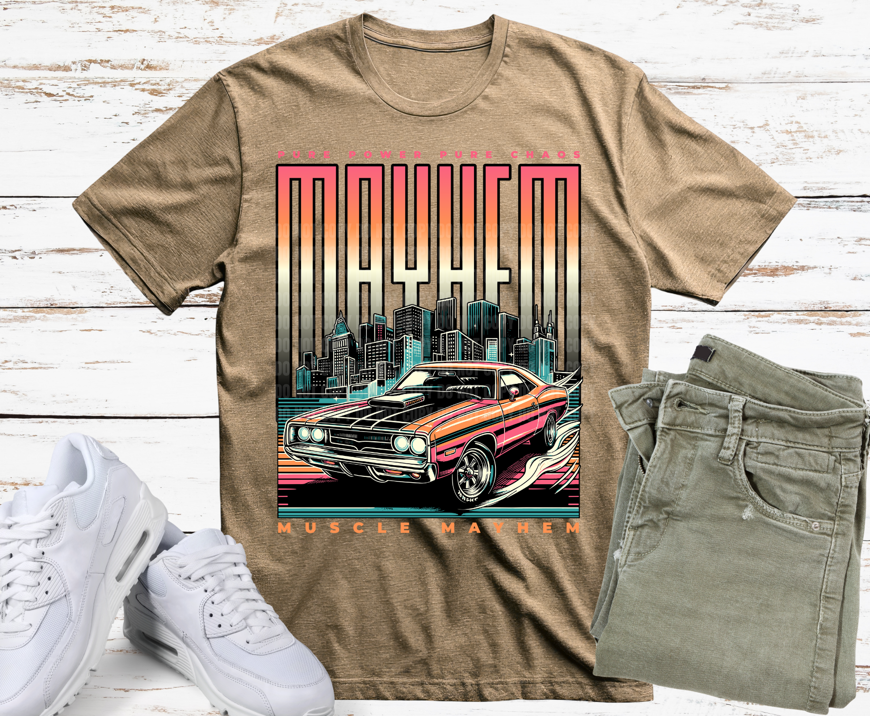 Beige t-shirt with a graphic of a muscle car and cityscape, paired with white sneakers and green jeans on a wooden surface.