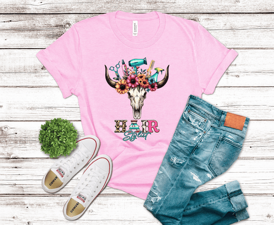 Pink t-shirt with floral bull skull design, white sneakers, and blue jeans on a wooden surface