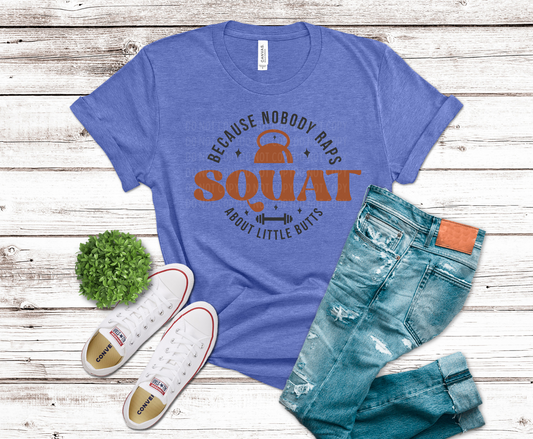 Blue t-shirt with humorous print, jeans, and sneakers on a wooden surface