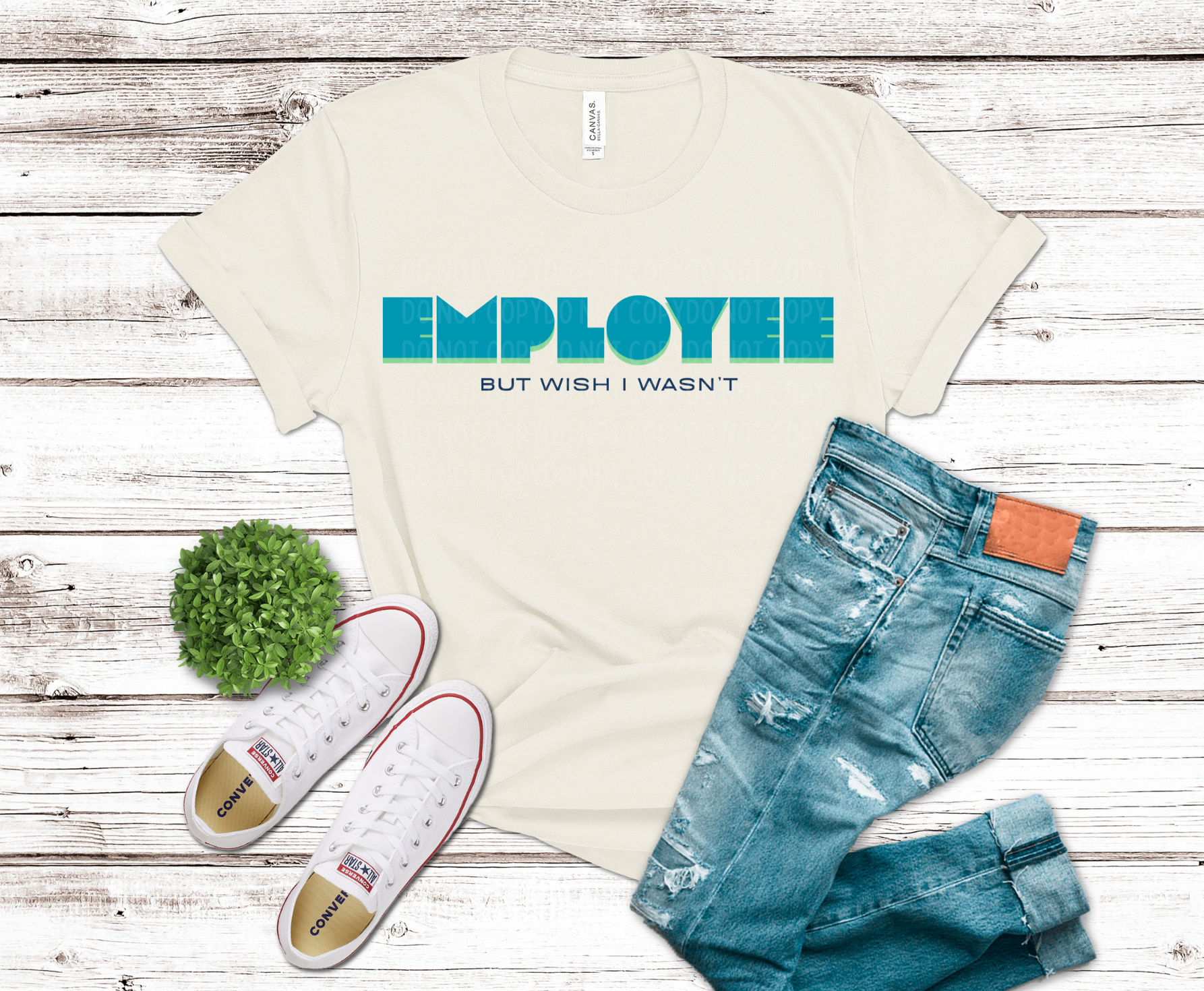 T-shirt with 'Employee but wish I wasn't' text, jeans, and sneakers on a wooden surface