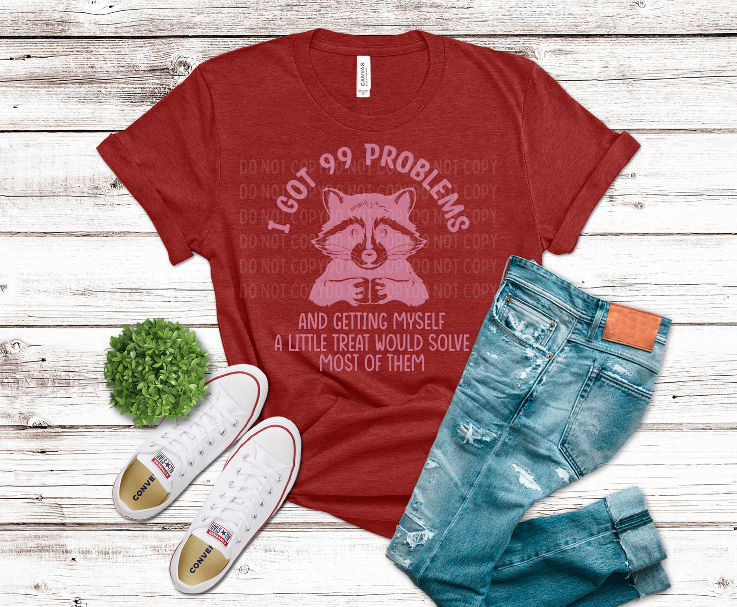 Red t-shirt with graphic design, white sneakers, and blue jeans on a wooden surface