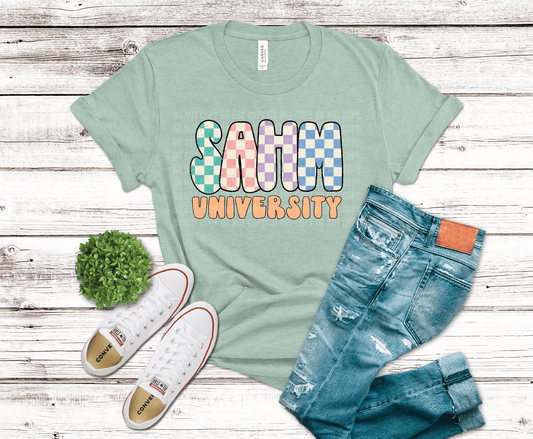 Light green t-shirt with 'Samm University' text, blue jeans, and white sneakers on a wooden surface.
