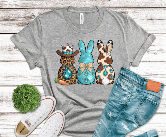 Western Easter bunny trio with cow print, leopard print, and turquoise marble finish featuring rhinestone style jewelry and glam bow design for boutique cowgirl shirts