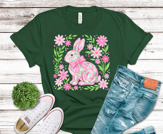 Pink bunny surrounded by spring flowers with a bow.