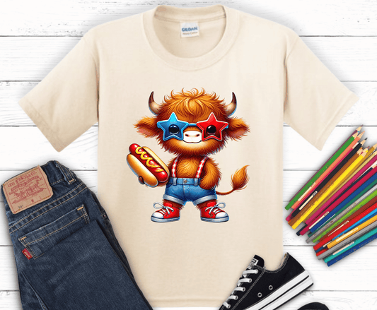Highland cow wearing patriotic glasses holding hotdog.