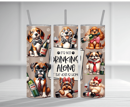 Humorous 20oz tumbler sublimation wrap featuring multiple cute cartoon dogs dressed up with bow ties and holding wine bottles and glasses, with the text "It's Not Drinking Alone If The Dog Is Home" and paw print background.